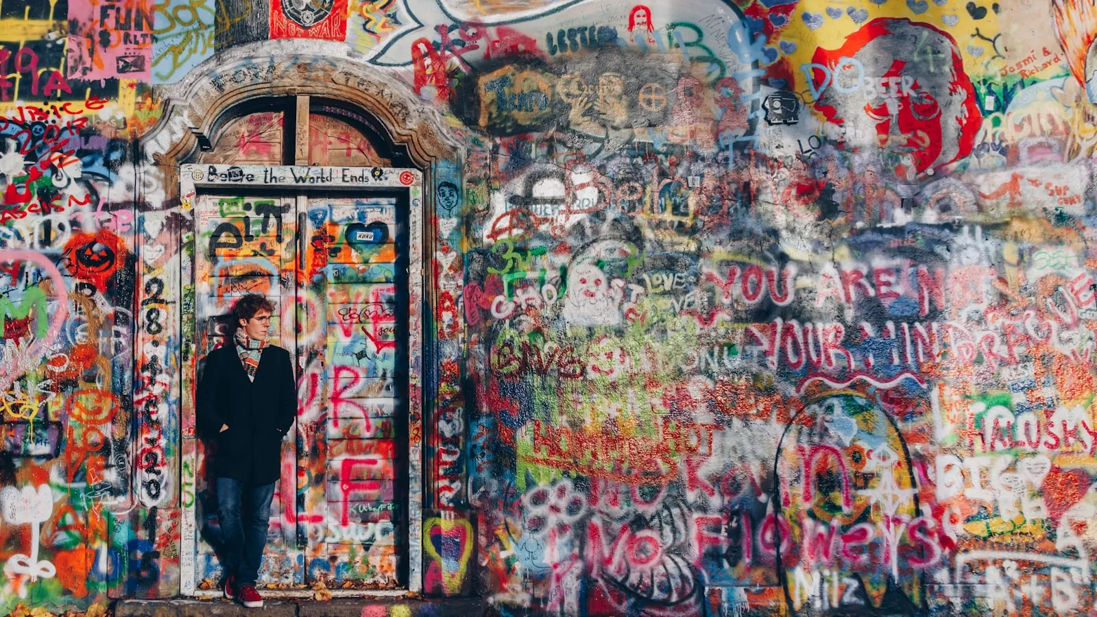 Fargerik, tett graffiti-malt vegg med en person ved en gammel dør